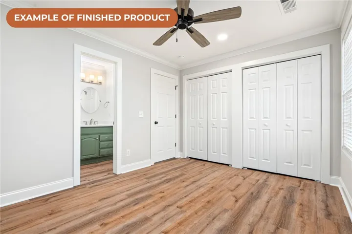 Well-lit living space with wood plank flooring and convenient access to a modern vanity.