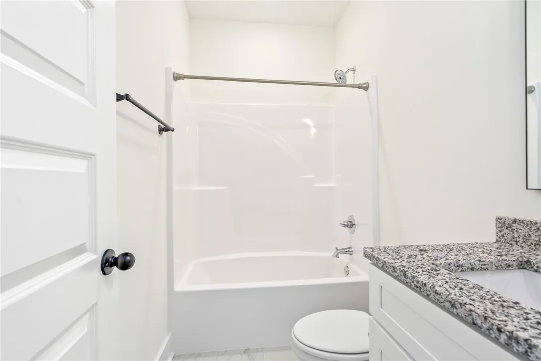 A well-appointed bath features a shower-tub combination and a vanity with granite counters.