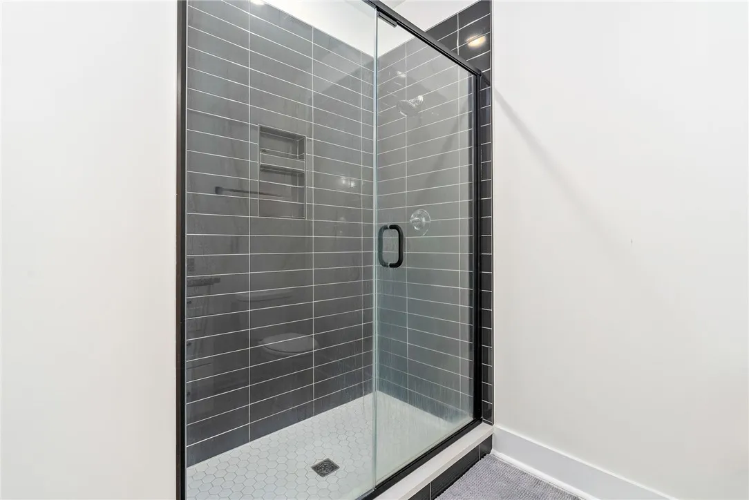 A sleek, enclosed shower with dark tile walls and a hexagonal tile floor, perfect for modern living.