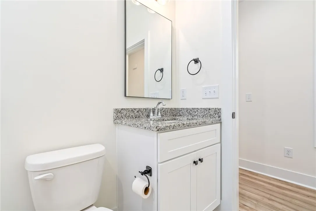 White cabinetry, a granite counter, and a sleek mirror define this practical bathroom vanity.