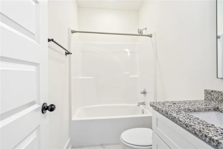 A well-appointed bath features a shower-tub combination and a vanity with granite counters.