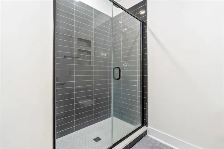 A sleek, enclosed shower with dark tile walls and a hexagonal tile floor, perfect for modern living.