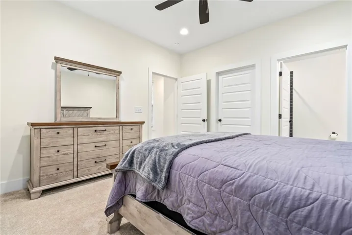 Relax in this tranquil bedroom, featuring a warm carpeted floor and efficient ceiling fan for comfort.