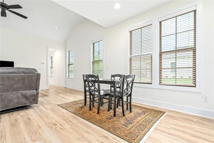 Natural light bathes this comfortable dining space, boasting high vaulted ceilings and durable wood flooring.