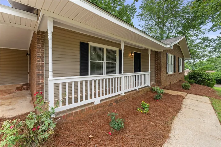 A welcoming front porch with white railings complements the classic brick and siding exterior.