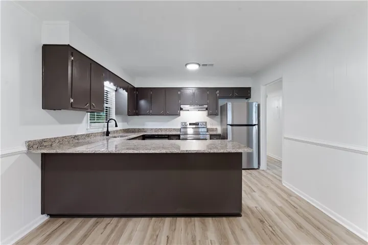 A well-appointed kitchen features dark cabinetry, granite-style countertops, and sleek stainless steel appliances.