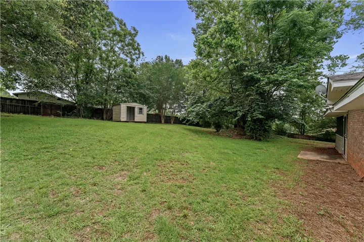 backyard with mature trees and a functional storage shed for all your outdoor needs.