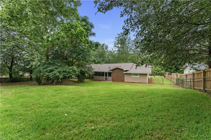 Green landscaping surrounds a welcoming brick-accented residence with an inviting screened porch.