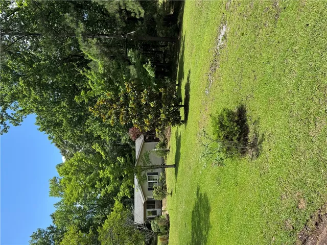 Mature trees and a manicured lawn embrace this inviting residence, providing ample outdoor space.
