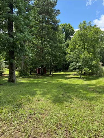 A verdant, tree-lined yard offers a tranquil outdoor retreat with ample space.