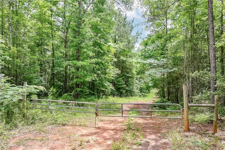 Secure gated entry welcomes you to a private, verdant lot with mature trees.