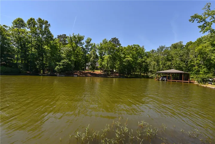 A tranquil lake view property features a private boat dock and lush green surroundings.