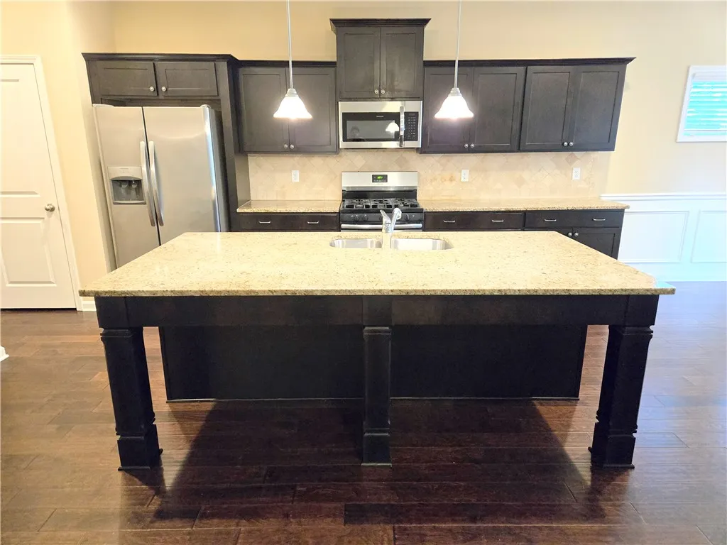 A well-appointed culinary space featuring granite countertops and dark wood cabinetry.
