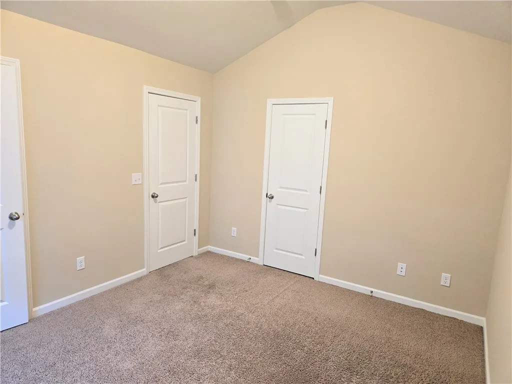 A comfortable bedroom with vaulted ceilings and plush carpet, ready for personalization.