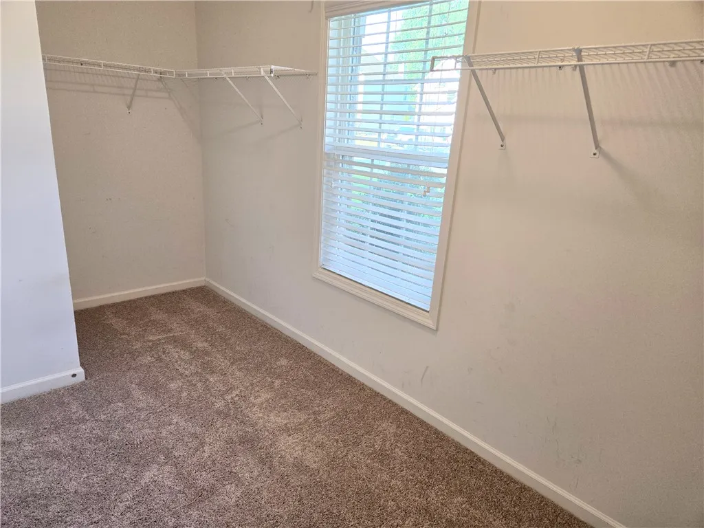 Well-lit walk-in closet offers ample storage with convenient shelving.