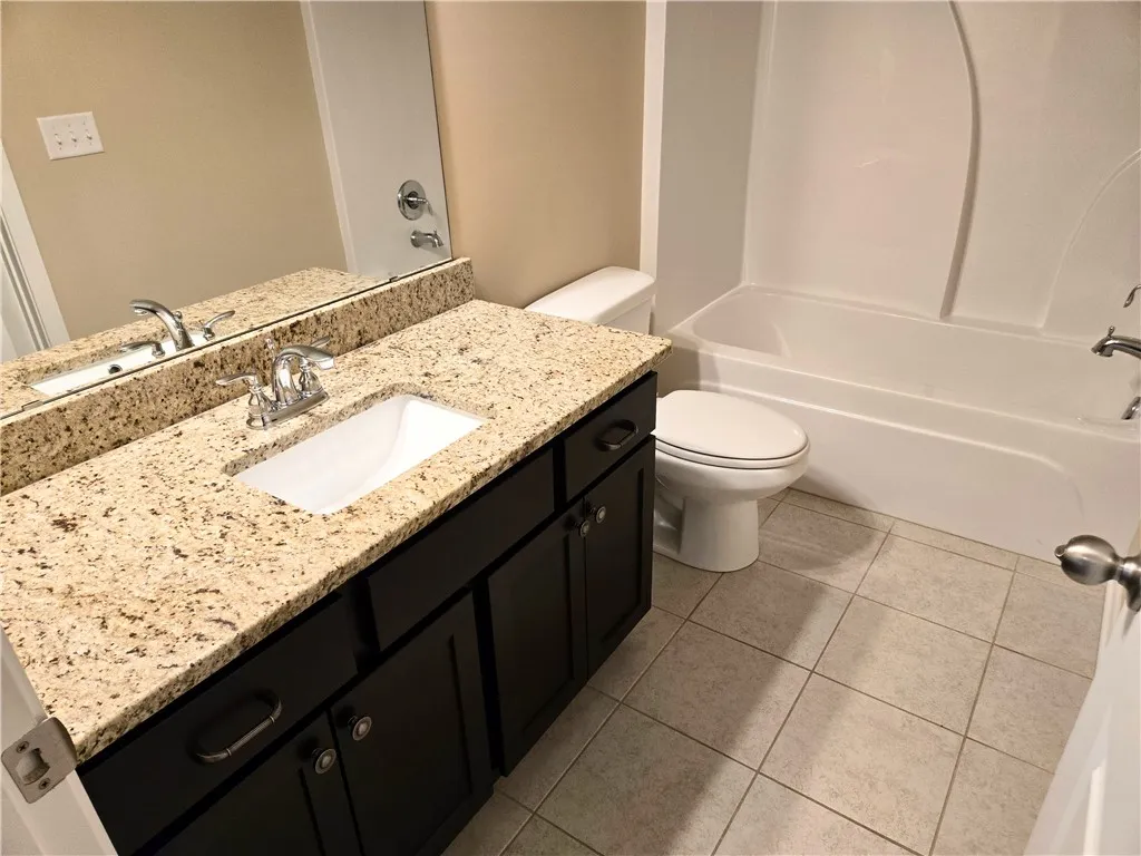 A well-appointed bathroom features a spacious granite counter vanity and practical tub-shower combination.