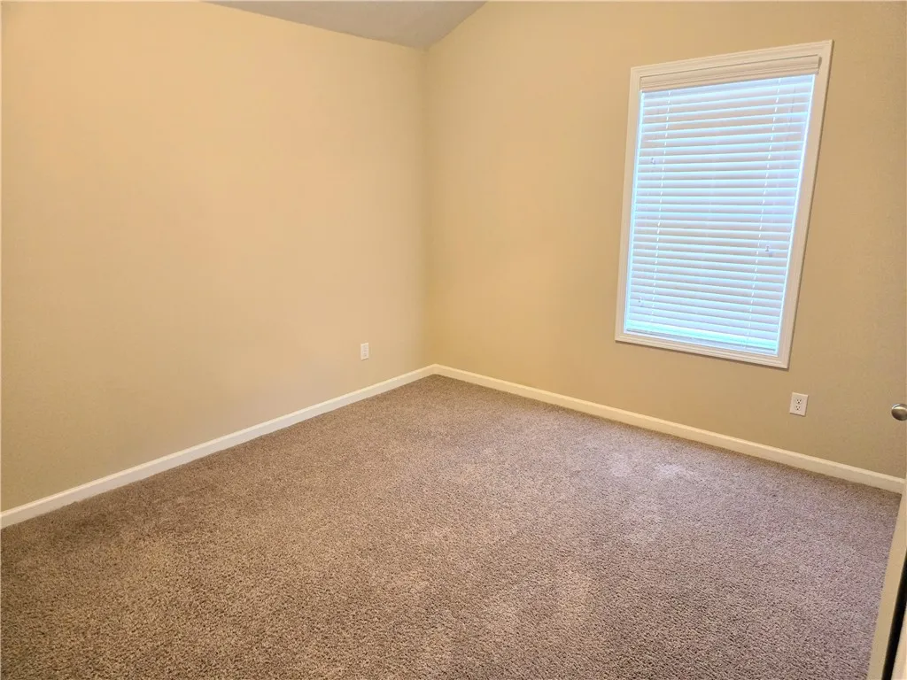Comfortable carpet and a well-lit window define this inviting space, perfect for quiet retreat.