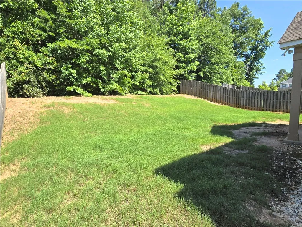A spacious, fenced backyard offers private outdoor living, framed by mature trees.