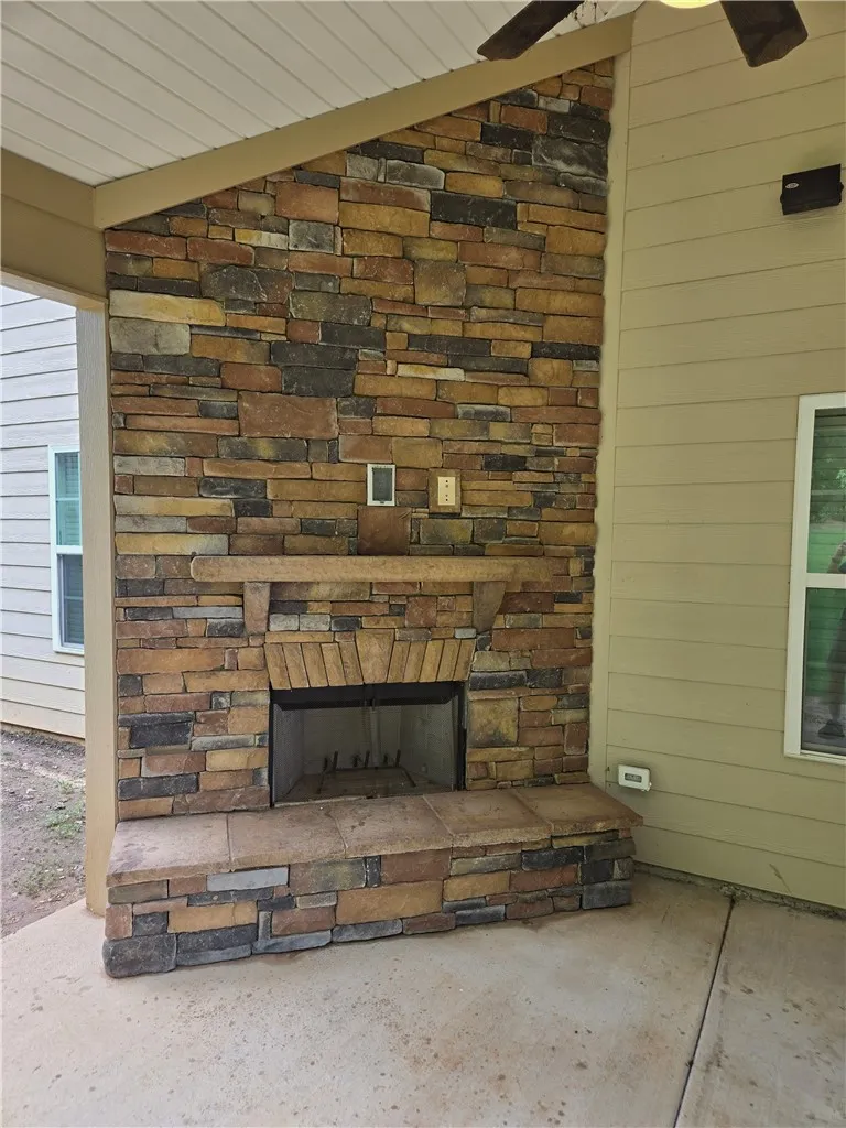 An inviting outdoor living space features a handsome stone fireplace on a concrete patio.