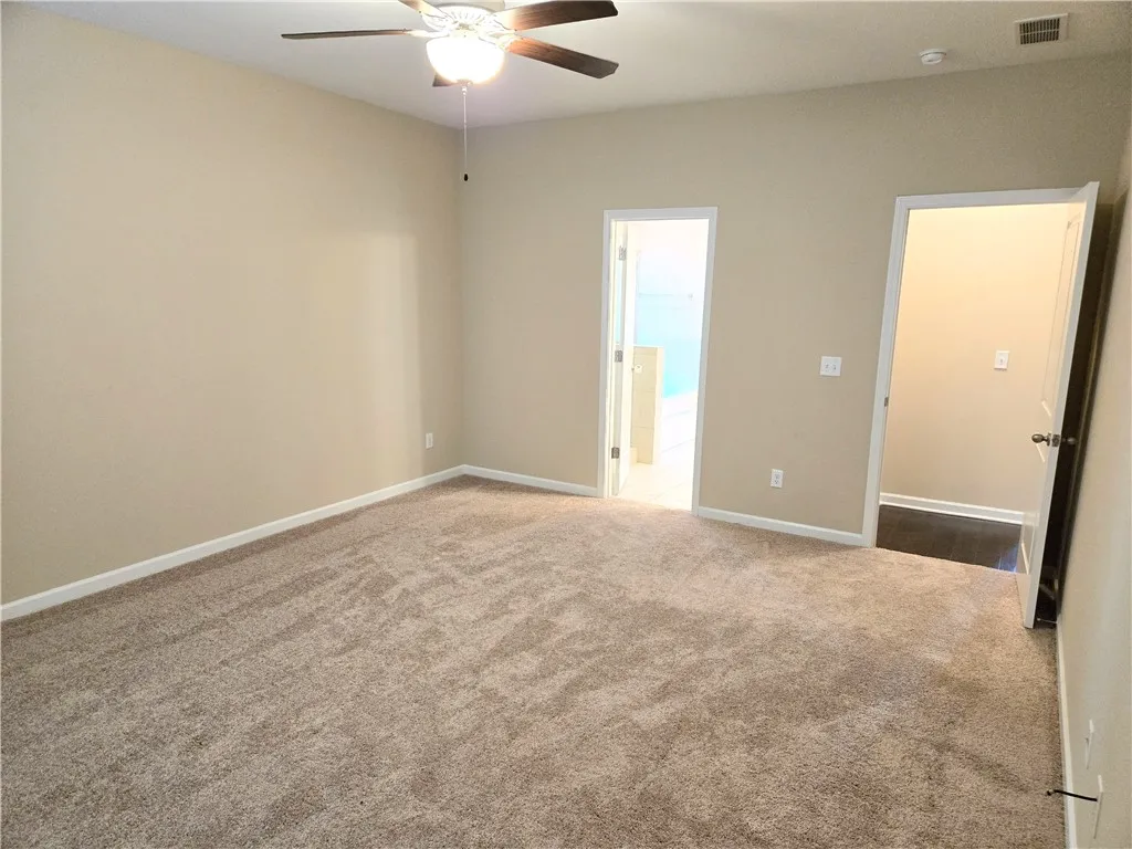 An inviting sleeping space with warm tones features an overhead ceiling fan for optimal comfort.