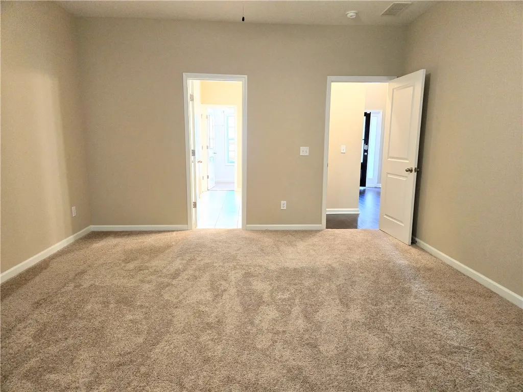 A spacious room offers plush carpeting and convenient access to adjacent areas.