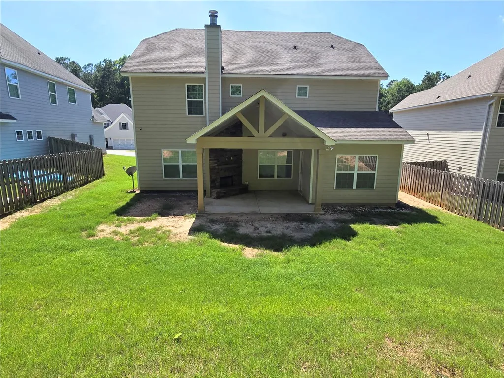 A private backyard oasis features a covered patio with a stone fireplace, ideal for outdoor entertaining.