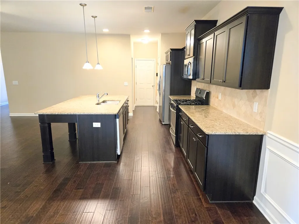 A well-appointed kitchen showcasing dark cabinetry, rich hardwood flooring, and granite countertops.