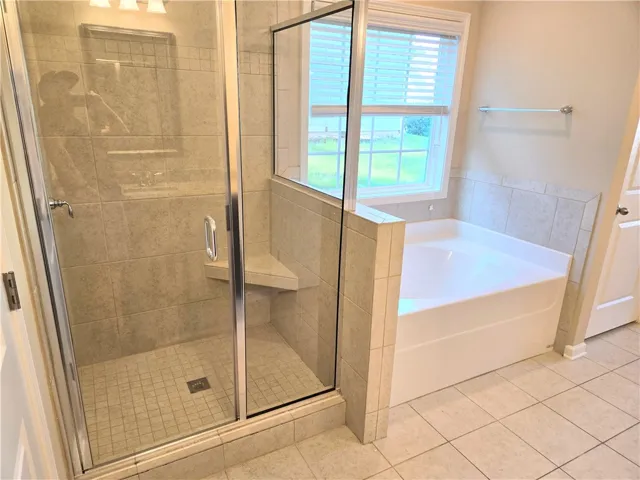 A well-appointed bath features a spacious soaking tub alongside a glass-enclosed shower.