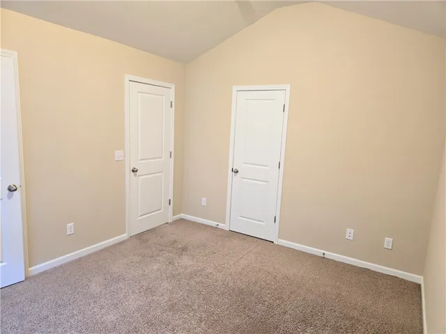 A comfortable bedroom with vaulted ceilings and plush carpet, ready for personalization.