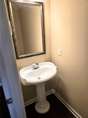 A refined pedestal sink with a framed mirror elevates this well-appointed bathroom.
