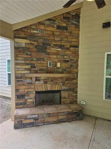 An inviting outdoor living space features a handsome stone fireplace on a concrete patio.