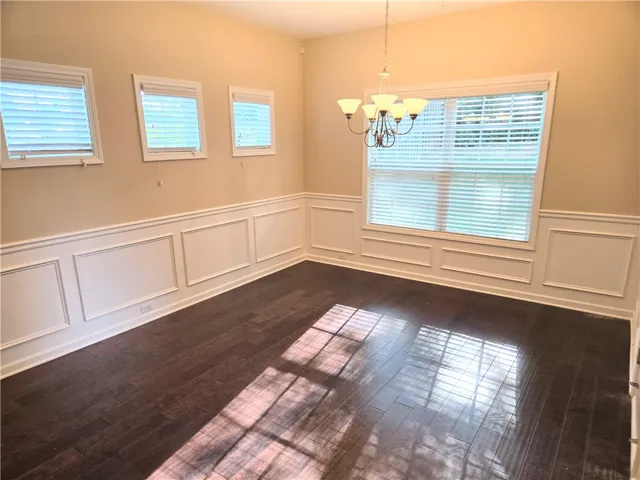 Rich hardwood flooring complements elegant wainscoting and natural light in this refined dining space.