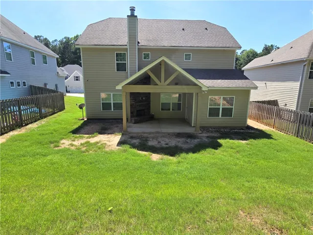 A private backyard oasis features a covered patio with a stone fireplace, ideal for outdoor entertaining.