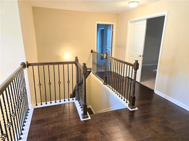 Rich hardwood flooring graces this upper-level landing, featuring a decorative iron balustrade leading to the lower level.