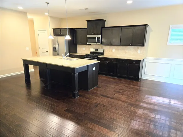 A grand central island anchors this kitchen, perfectly complemented by dark cabinetry and lustrous hardwood floors.