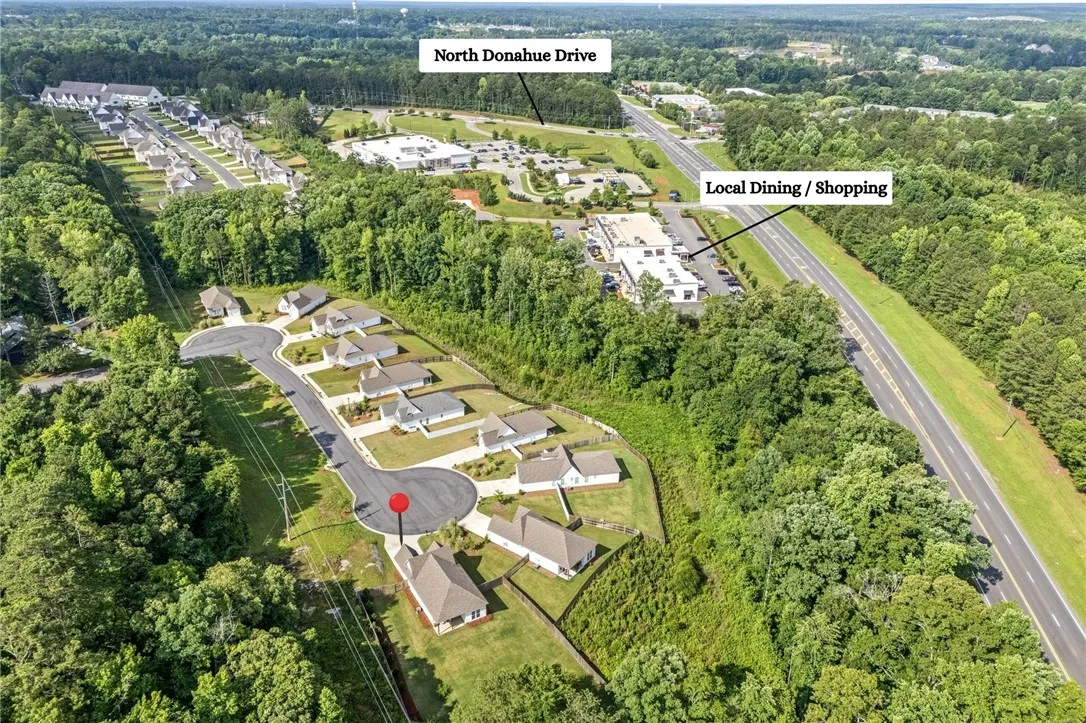 An aerial perspective showcases a vibrant community nestled within abundant greenery, offering both residential tranquility and convenient access to commercial amenities.