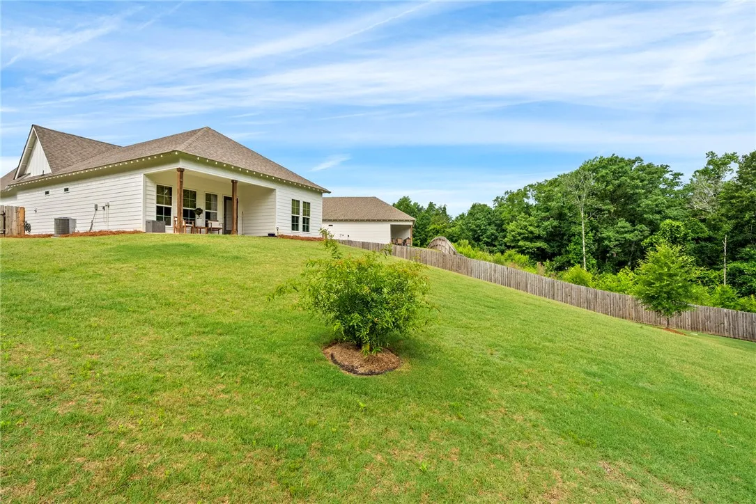 A gently sloping green yard leads to a charming white residence with a welcoming covered porch.