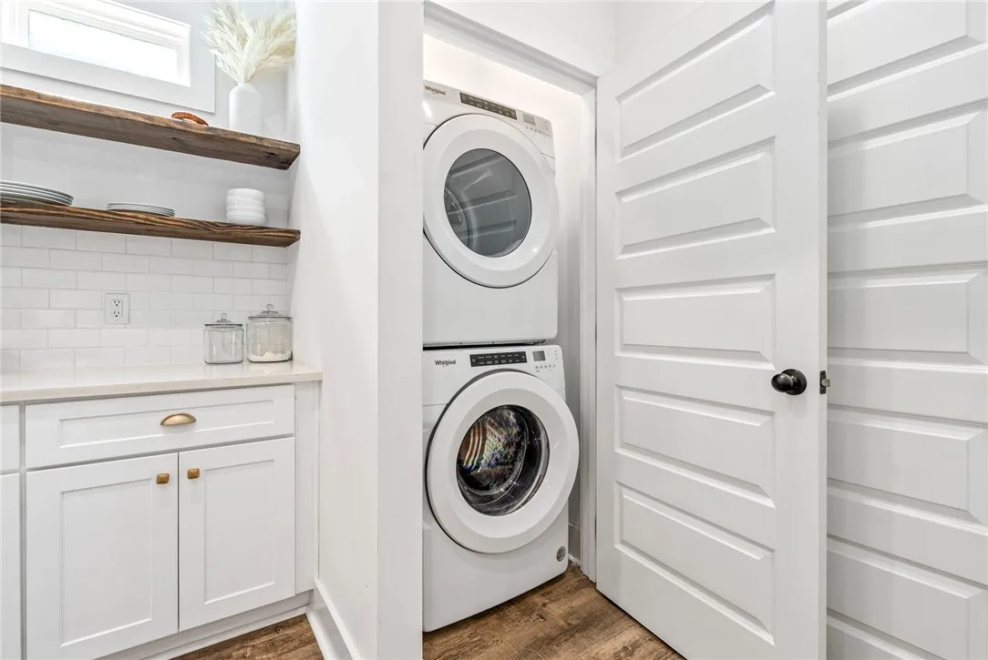 Streamlined laundry closet featuring a stacked washer and dryer, adjacent to practical counter space and open shelving.