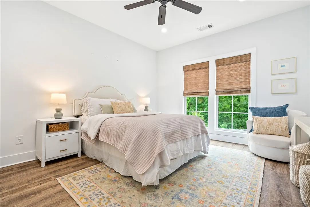 Hardwood flooring pairs with an upholstered headboard, creating a serene and well-lit bedroom.