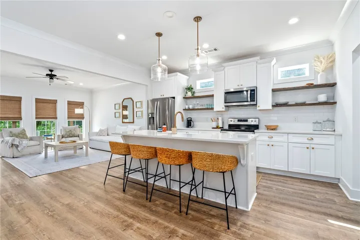 An open-concept living space with warm wood flooring transitions seamlessly from kitchen to living room.
