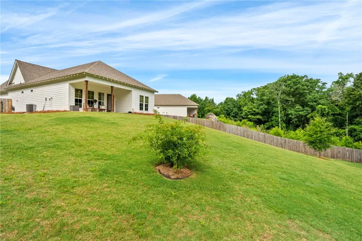 A gently sloping green yard leads to a charming white residence with a welcoming covered porch.