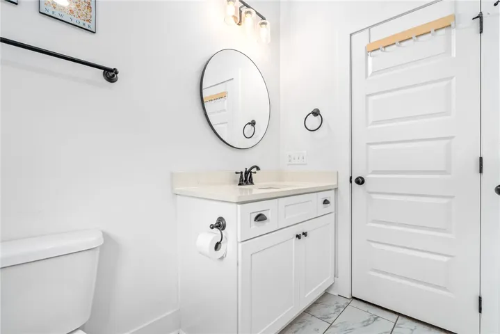 A well-appointed bathroom features a crisp white vanity and a round mirror, offering both style and utility.