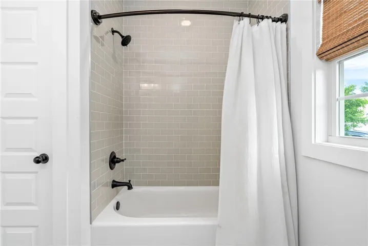 A pristine bath and shower combo with subtle subway tile accents and ample natural light.