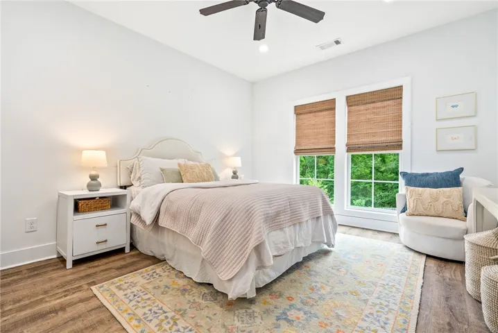 Hardwood flooring pairs with an upholstered headboard, creating a serene and well-lit bedroom.
