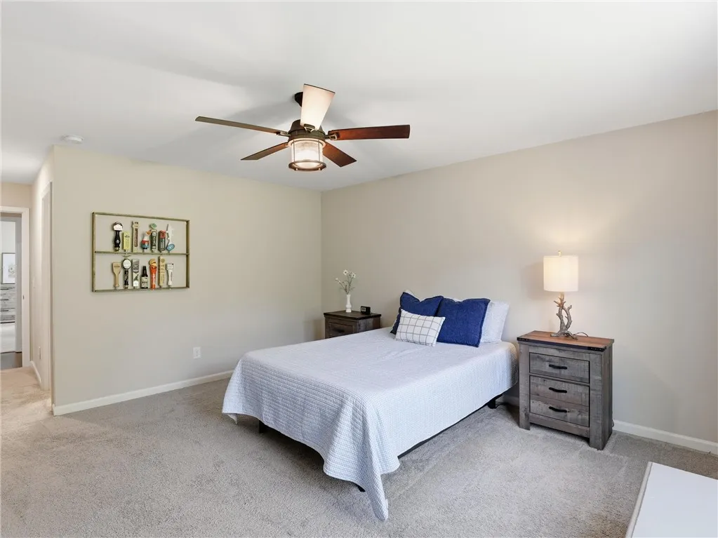 Plush carpeting and a classic ceiling fan create a serene and comfortable bedroom retreat.