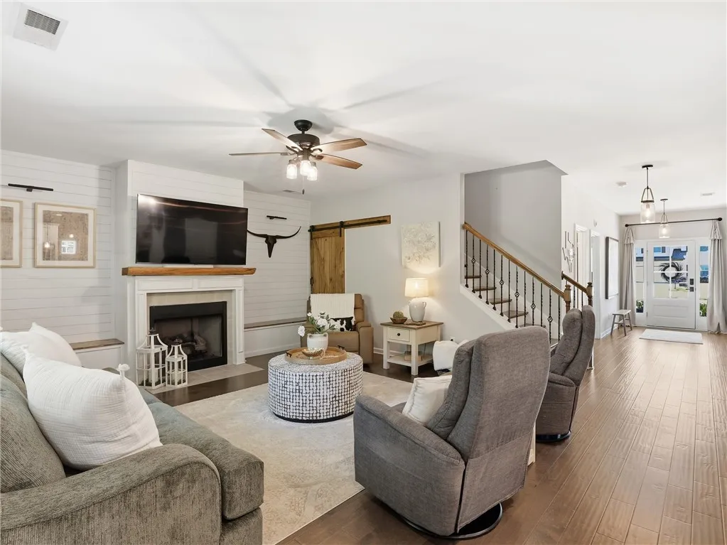 A welcoming living room featuring a cozy fireplace and rich hardwood flooring, flowing into a bright entryway.