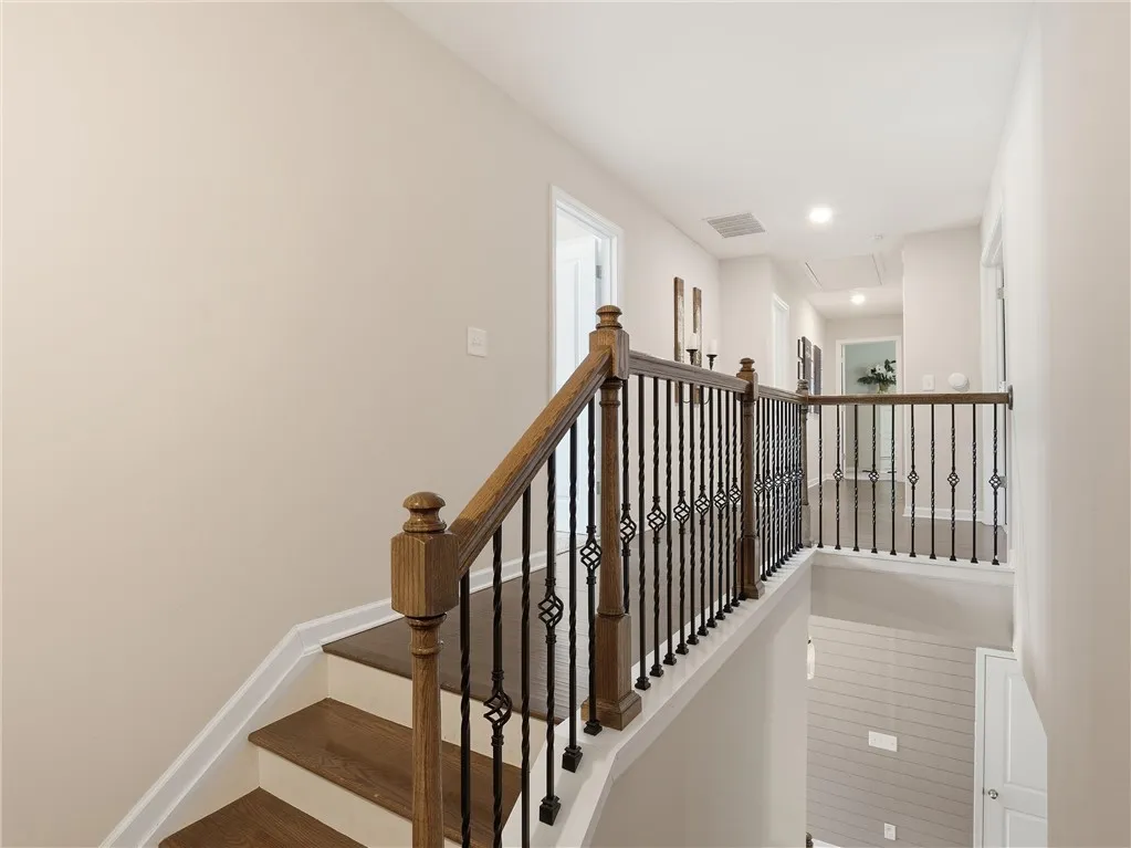Elegant hardwood stairs and wrought iron balusters lead to a bright upper landing with recessed lighting.
