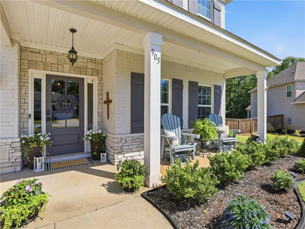A welcoming front porch features a seating area, charming landscaping, and a well-maintained entry.