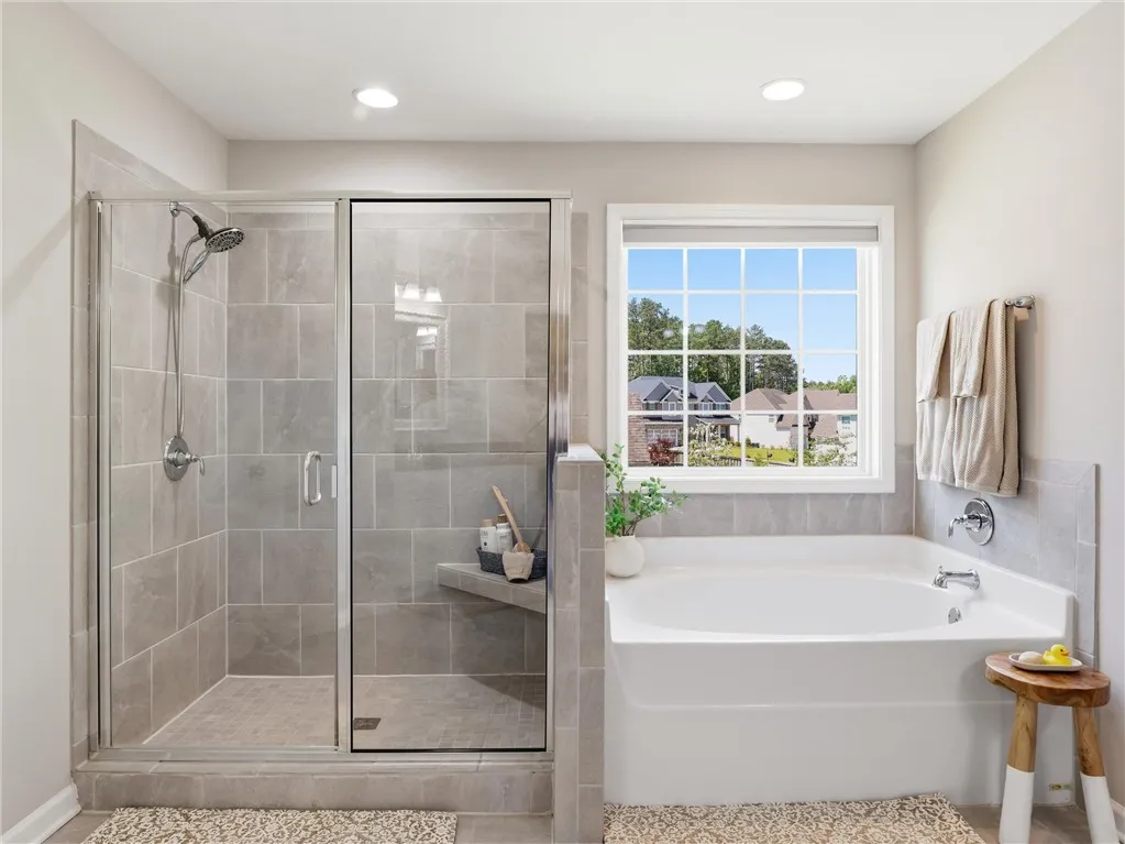 A well-appointed bath features a tiled walk-in shower and a garden tub beneath a bright window.