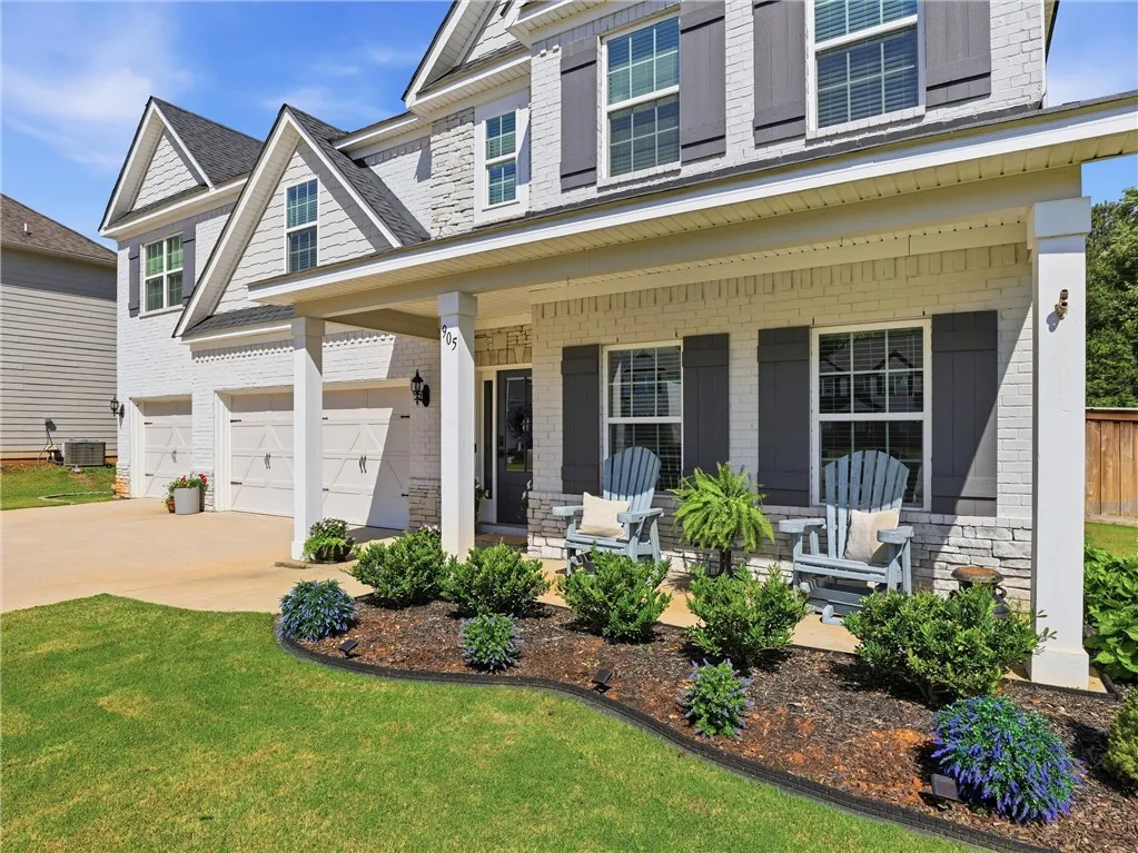 A welcoming facade with a covered entry, adorned with manicured landscaping and a dual garage.
